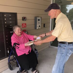 A volunteer hands a meal to a Meals on Wheels participant.